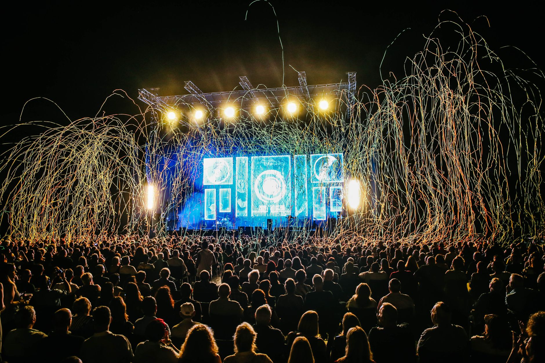 Palco de festival iluminado diante de uma grande plateia